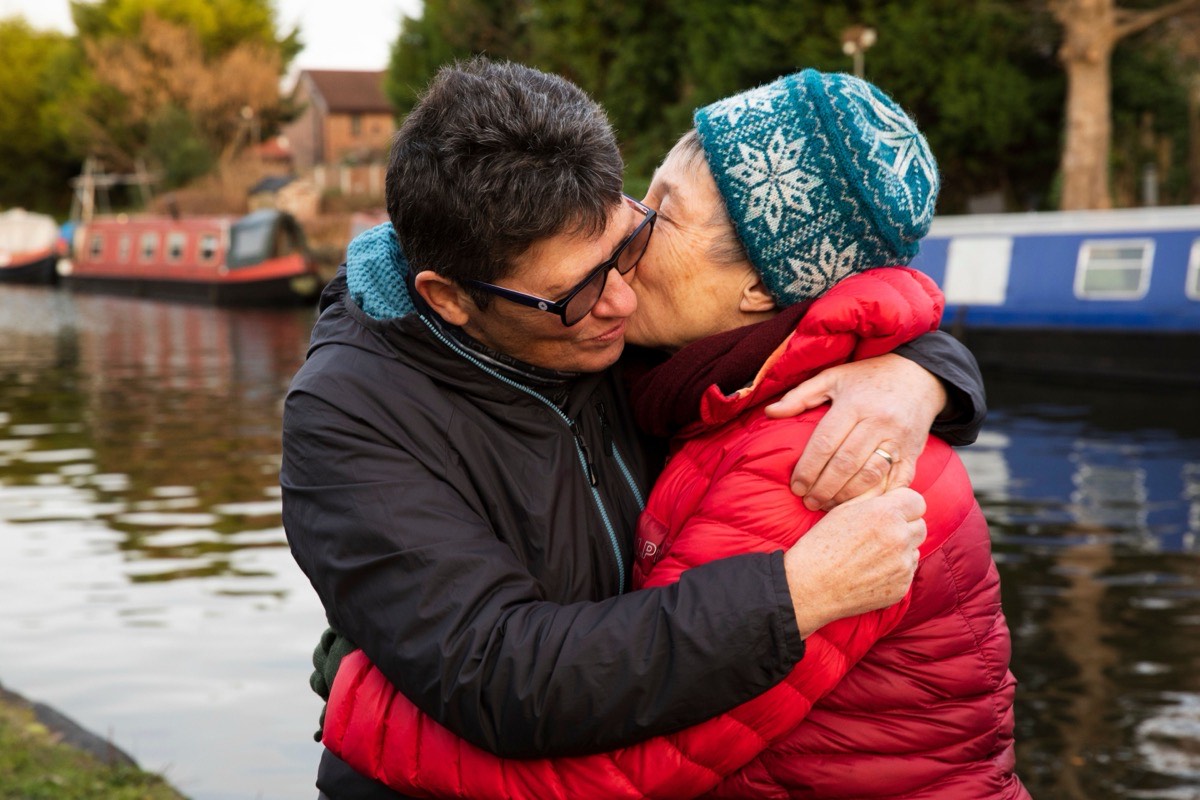 Mature couple embracing beside a UK canal with narrowboats