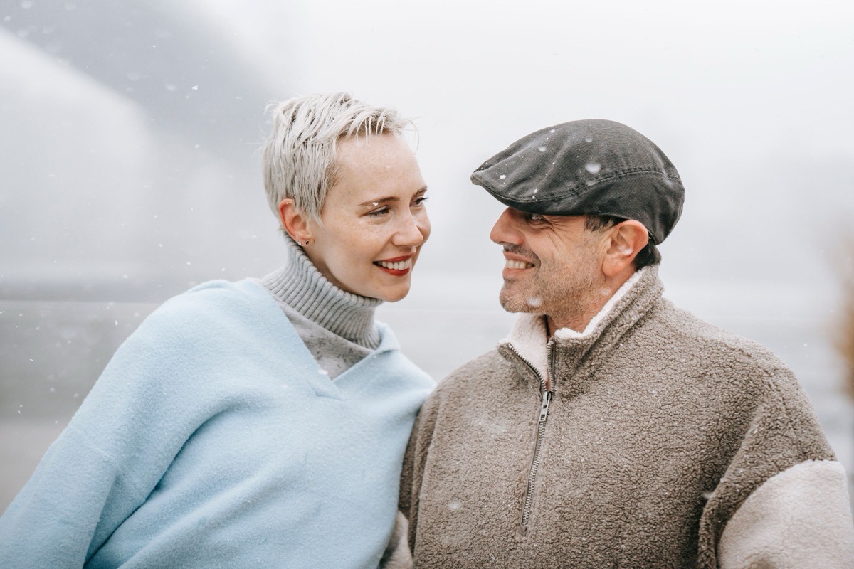 Mature couple smiling at each other in light snowfall