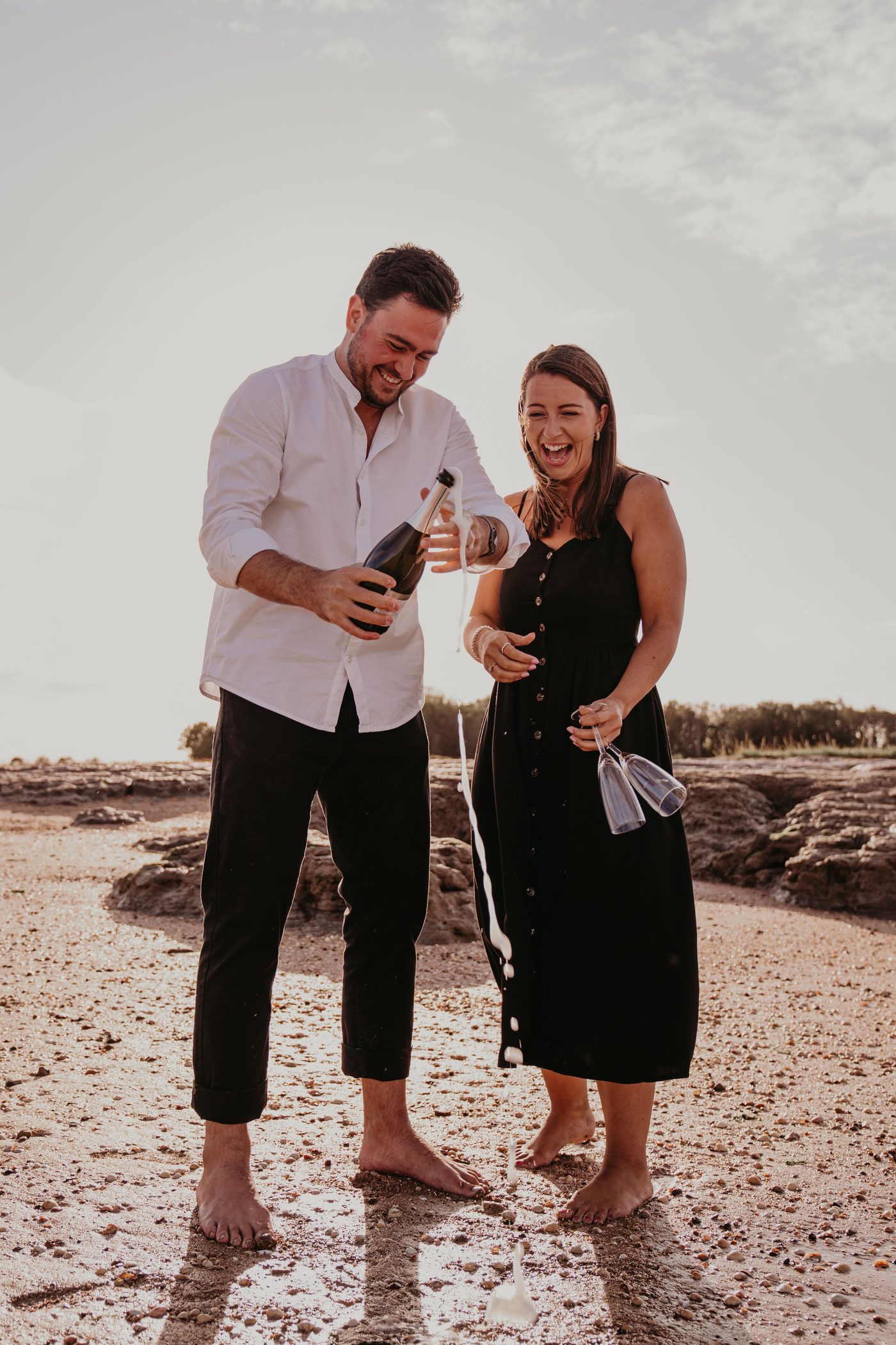 Mature couple celebrating with champagne on a beach