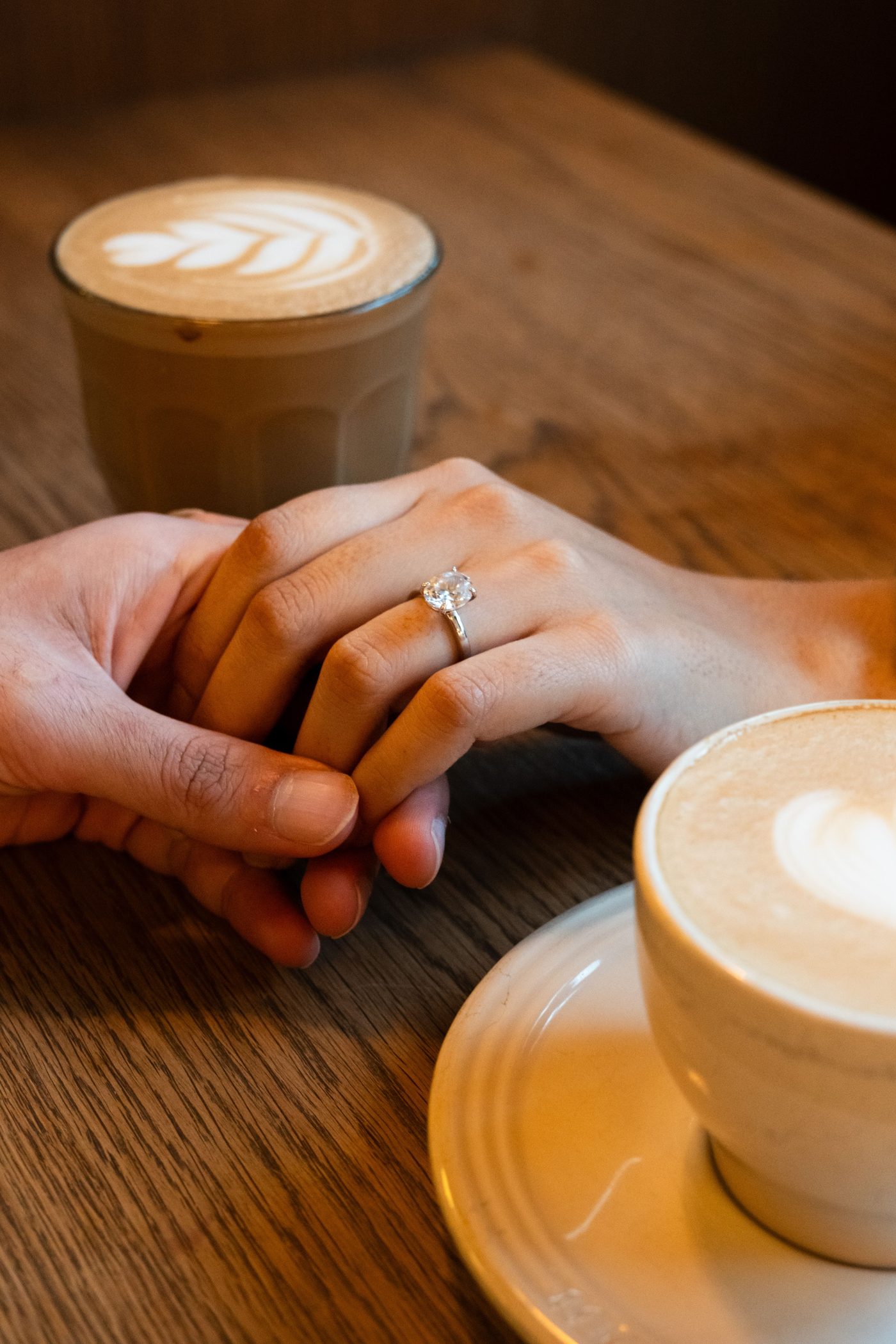 Couple holding hands over coffee at a cafe table